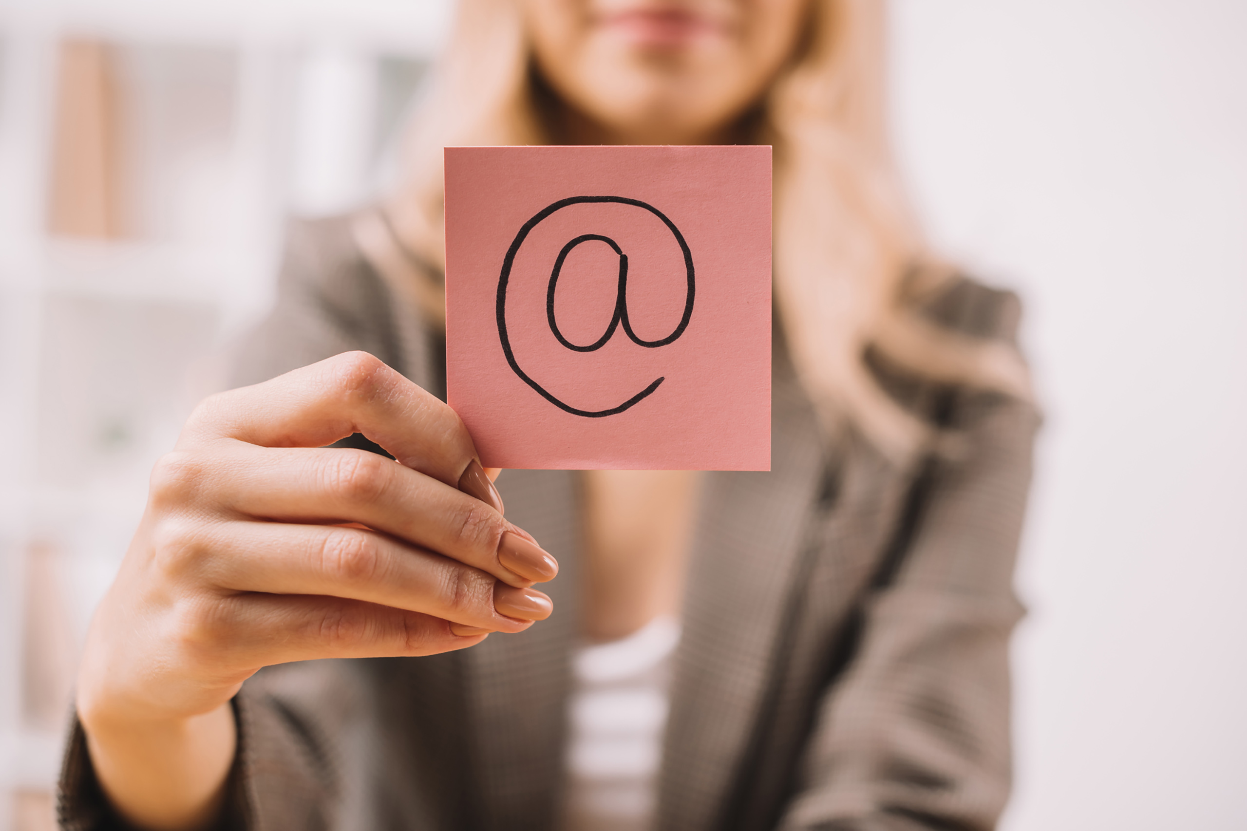 Woman holding note with large @ displayed