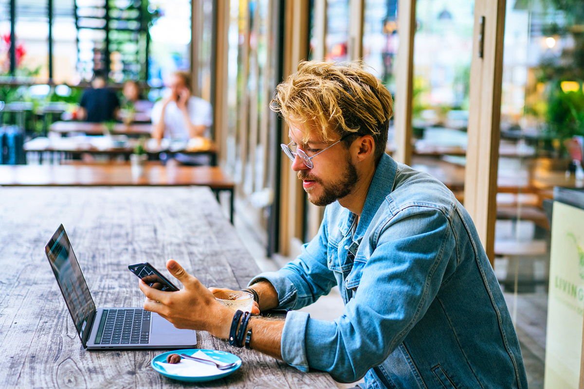 young attractive business man in a cafe works for a laptop, drinks coffee