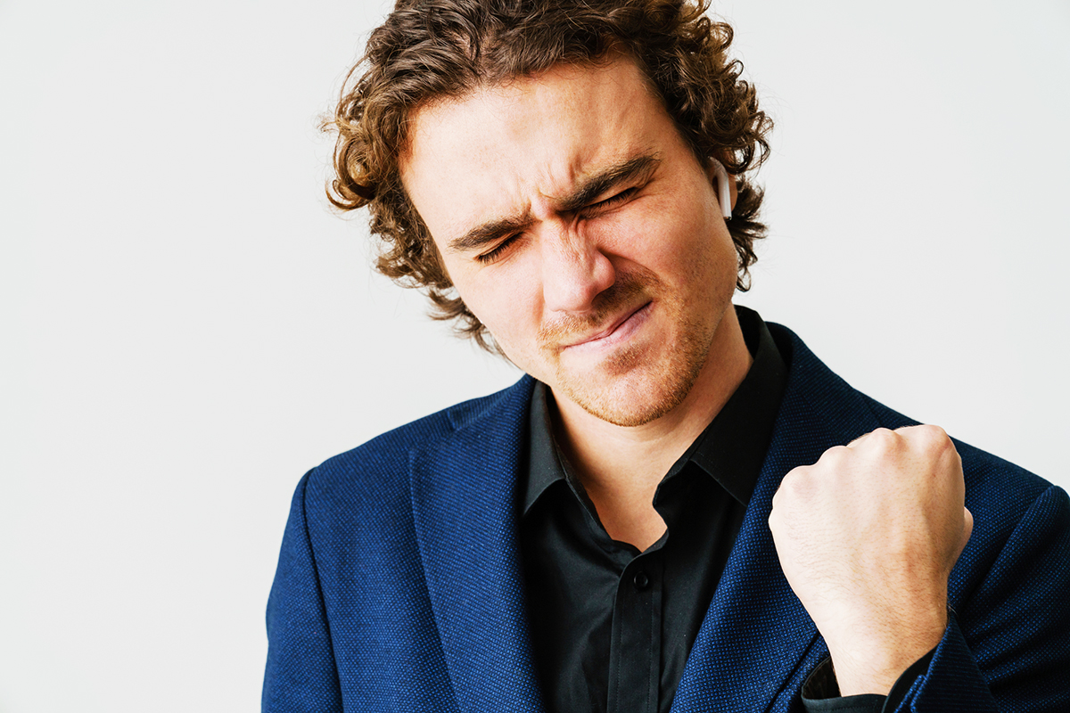 Excited handsome man in earphones making winner gesture isolated over white background